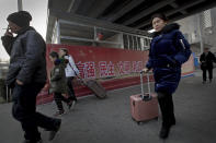 In this Jan. 12, 2019, photo, Chinese people walk by a worker welding steel frames near a billboard displaying a Chinese government propaganda message at the Central Business District in Beijing. China's slowing economy is squeezing the urban workers and entrepreneurs the ruling Communist Party is counting on to help transform this country from a low-wage factory floor into a prosperous consumer market. (AP Photo/Andy Wong)