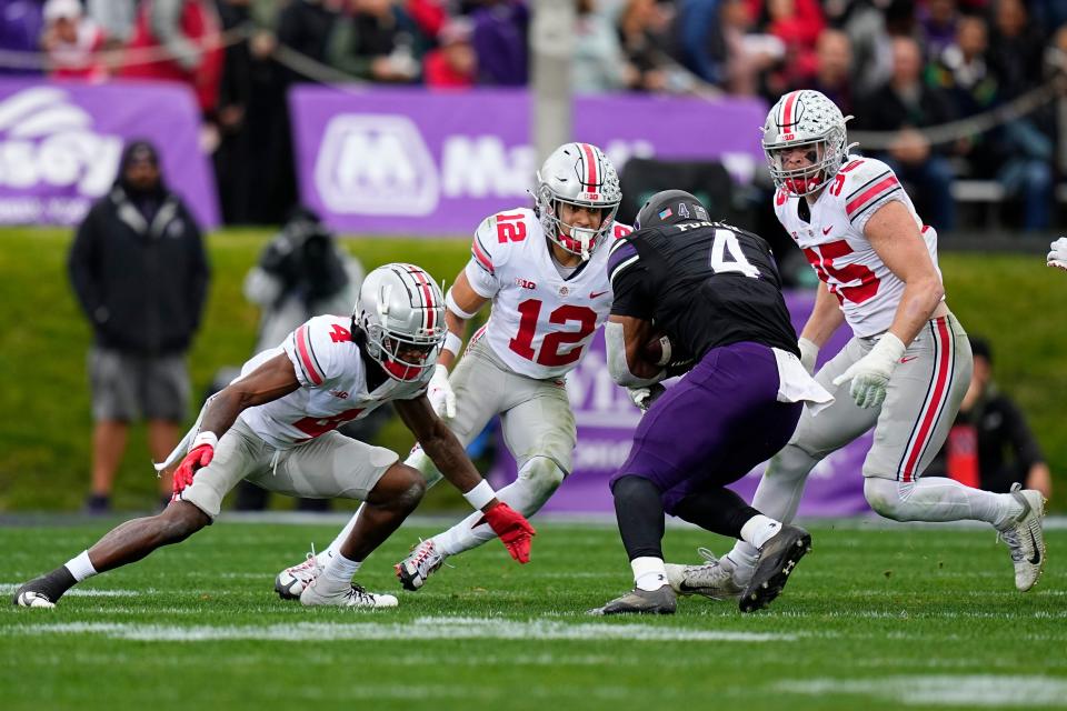 Nov 5, 2022; Evanston, Illinois, USA; Ohio State Buckeyes cornerback JK Johnson (4), safety Lathan Ransom (12) and linebacker Tommy Eichenberg (35) swarm Northwestern Wildcats running back Cam Porter (4) during the first half of the NCAA football game at Ryan Field. Mandatory Credit: Adam Cairns-The Columbus Dispatch