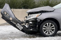 A wrecked car with ice build up sits on U.S. Highway 75 as emergency workers nearby work to remove it from the highway, Wednesday, Feb. 1, 2023, in Dallas. (AP Photo/Tony Gutierrez)