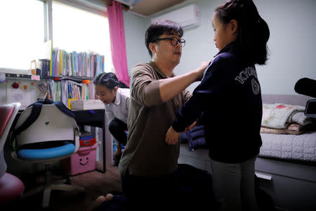 Lee Kyoung-min, a store manager at Lotte Mart, dresses his daughters before taking them to school, at their home in Seoul, South Korea, December 19, 2018. REUTERS/Kim Hong-Ji