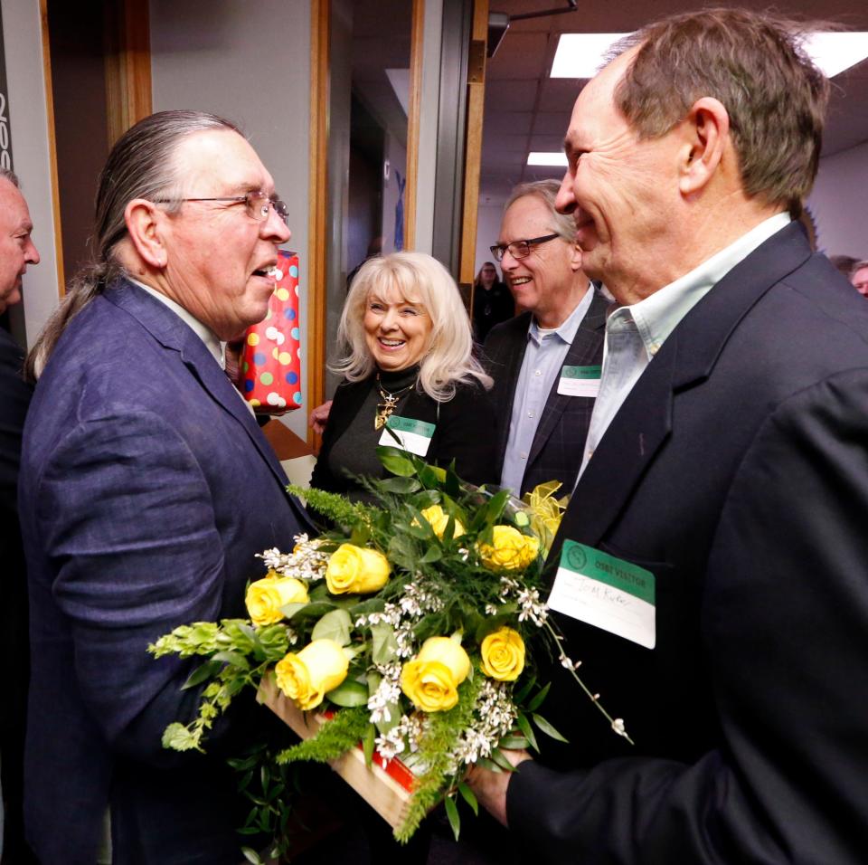 Artist Harvey Pratt, left, is given flowers for his wife by Tom Kuker during Pratt's retirement celebration on Friday, Feb. 24, 2017 in Oklahoma City, Okla.  At center are Sheri and Dr. Charles Farmer, parents of Girl Scout Murder victim Laurie Lee Farmer. The longtime OSBI forensic artist, Pratt retired in 2017 after 50 years in law enforcement.