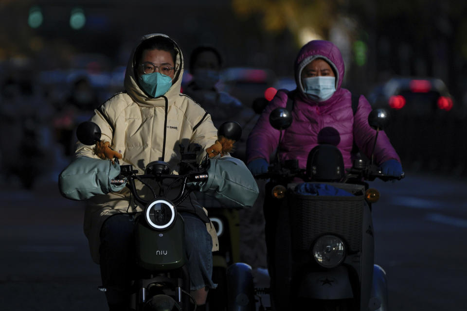 Motorists wearing face masks ride their electric-powered scooters on a street during the morning rush hour in Beijing, Monday, Oct. 31, 2022. (AP Photo/Andy Wong)