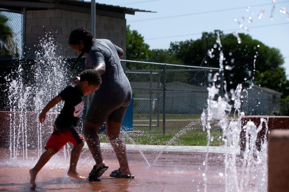 Cousins Jewelz Johnson, 13, and Treashawn T., 3, spin in circles at the West Haven Park Splash Pad Thursday, July 13, 2023.