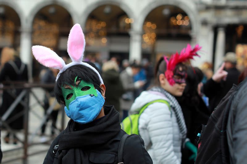 A carnival reveller wears a protective mask at Venice Carnival, which the last two days of, as well as Sunday night's festivities, have been cancelled because of an outbreak of coronavirus, in Venice