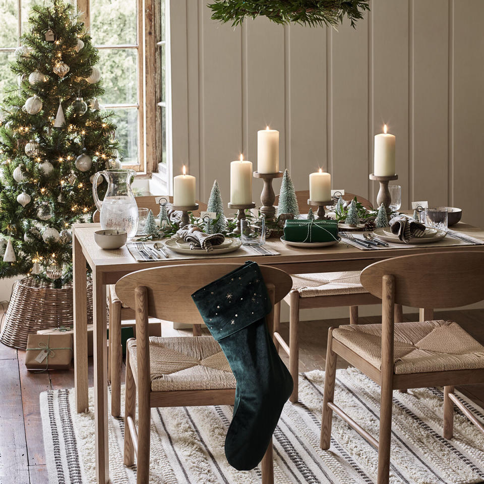 Weihnachtlich gedeckter Tisch mit Christbaum im Hintergund