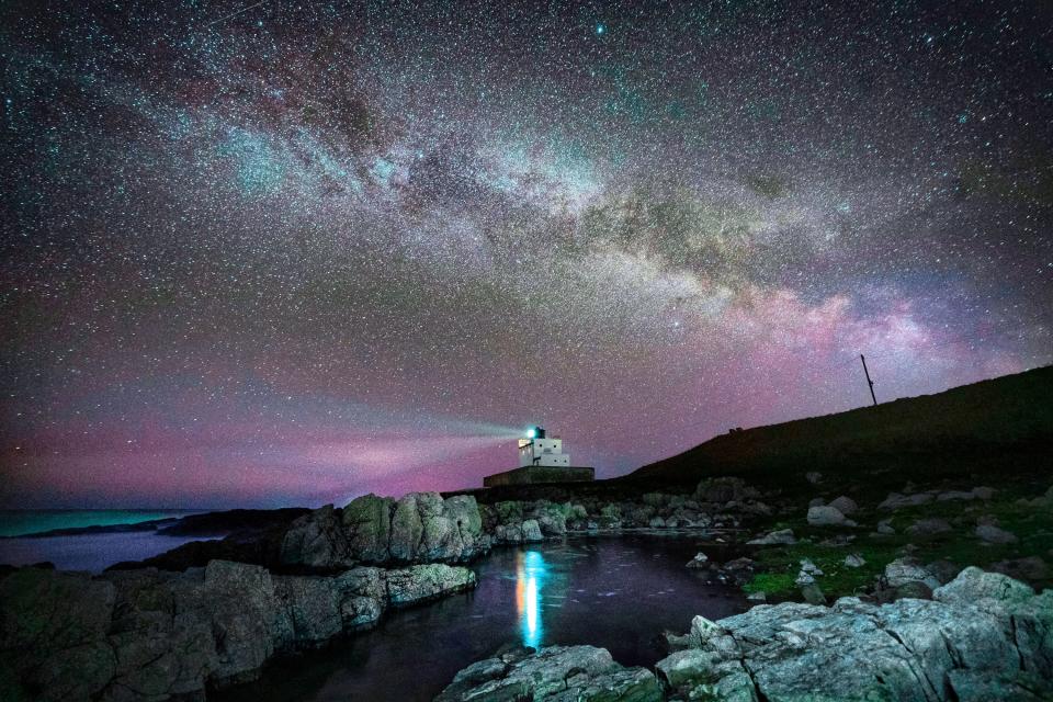 The core of the Milky Way becomes visible in the early hours of Tuesday morning as it moves over Bamburgh Lighthouse at stag Rock in Northumberland (PA)