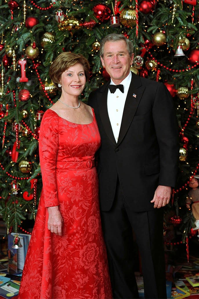 Laura and George W. Bush pose with several bright red Christmas tree ornaments, December 2003.