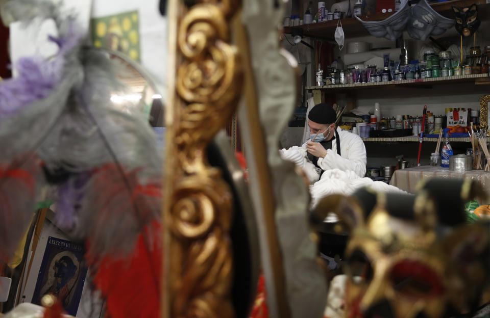 A Venetian artisan mask maker works on an item in a workshop in Venice, Italy, Saturday, Jan. 30, 2021. In another year, masks would be an accepted sign of gaiety in Venice, an accessory worn for games, parties and crowds. Since the onset of the COVID-19 pandemic face masks are worn now to protect, not amuse. (AP Photo/Antonio Calanni)