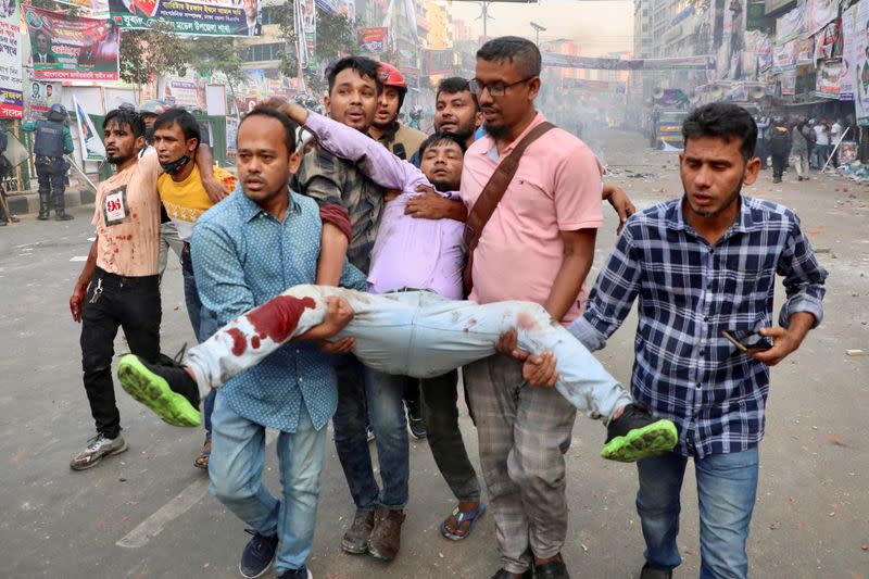 People carry an injured person during a clash between Bangladeshi police and Bangladesh Nationalist Party (BNP) activists who gathered in front of the party's central office in Dhaka