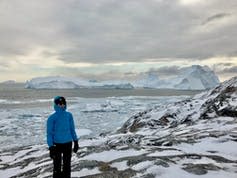 Michalea King, a glacier researcher, stands in front of bay full of icebergs.