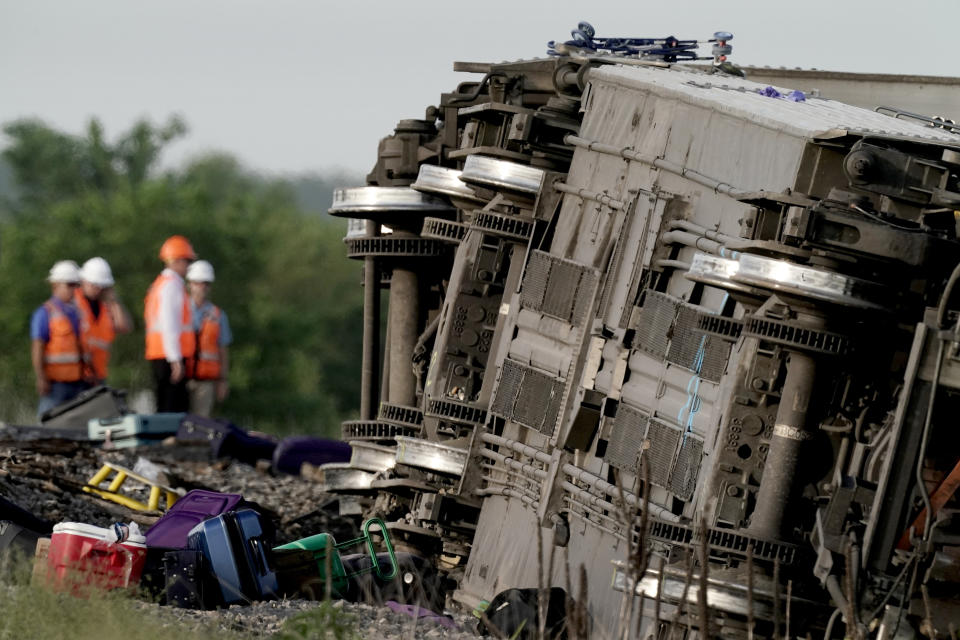 Workers inspect the scene of an Amtrak train which derailed after striking a dump truck Monday, June 27, 2022, near Mendon, Mo. (AP Photo/Charlie Riedel)