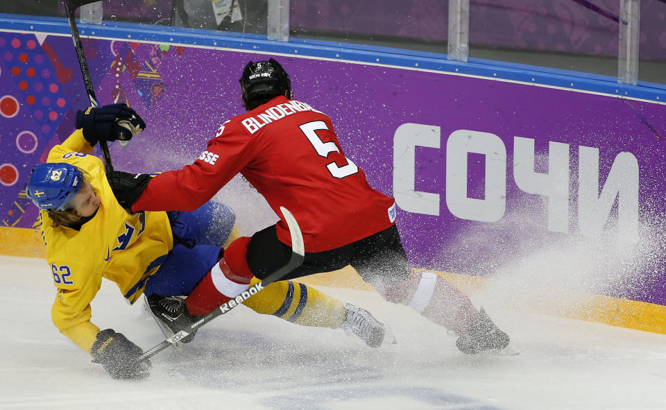 Sweden forward Carl Hagelin is knocked to the ice by Switzerland defenseman Severin Blindenbacher in the first period of a men's ice hockey game at the 2014 Winter Olympics, Friday, Feb. 14, 2014, in Sochi, Russia. (AP Photo/Julio Cortez)