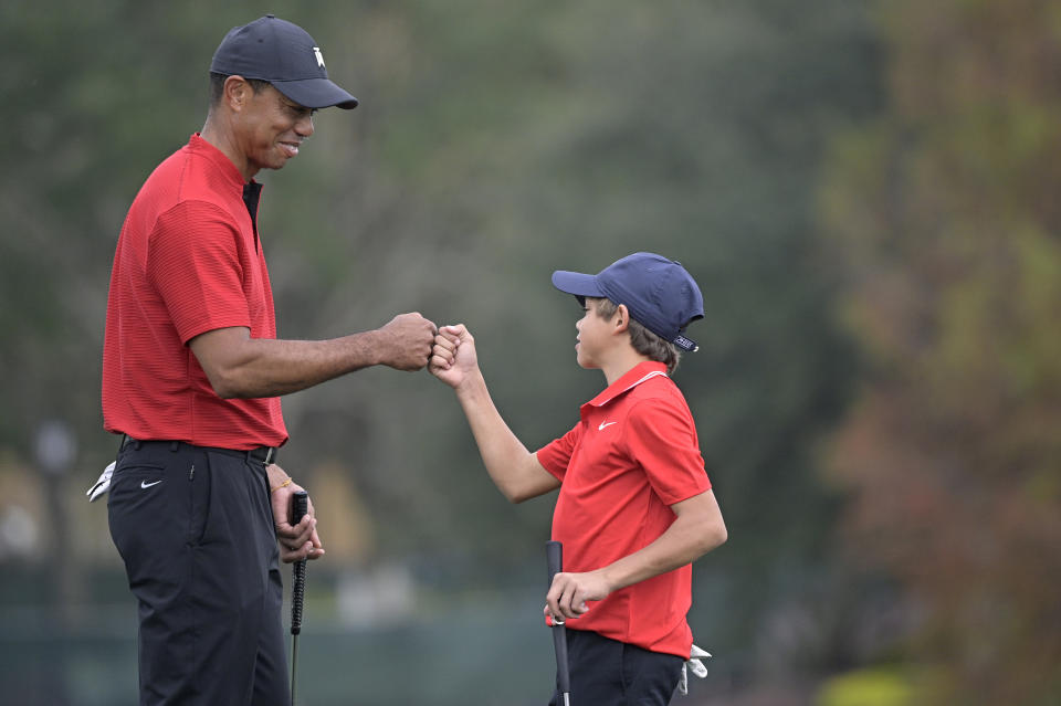 Tiger Woods, left, shares a fist-bump with his son Charlie after putting on the 18th green during the final round of the PNC Championship golf tournament, Sunday, Dec. 20, 2020, in Orlando, Fla. (AP Photo/Phelan M. Ebenhack)