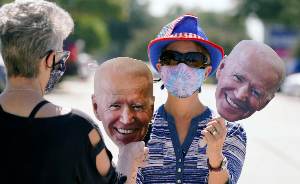 Phyllis Smith, rights, hands her friend Sabina Geiser a Joe Biden face before a Ridin' With Biden event Sunday, Oct. 11, 2020, in Plano, Texas.