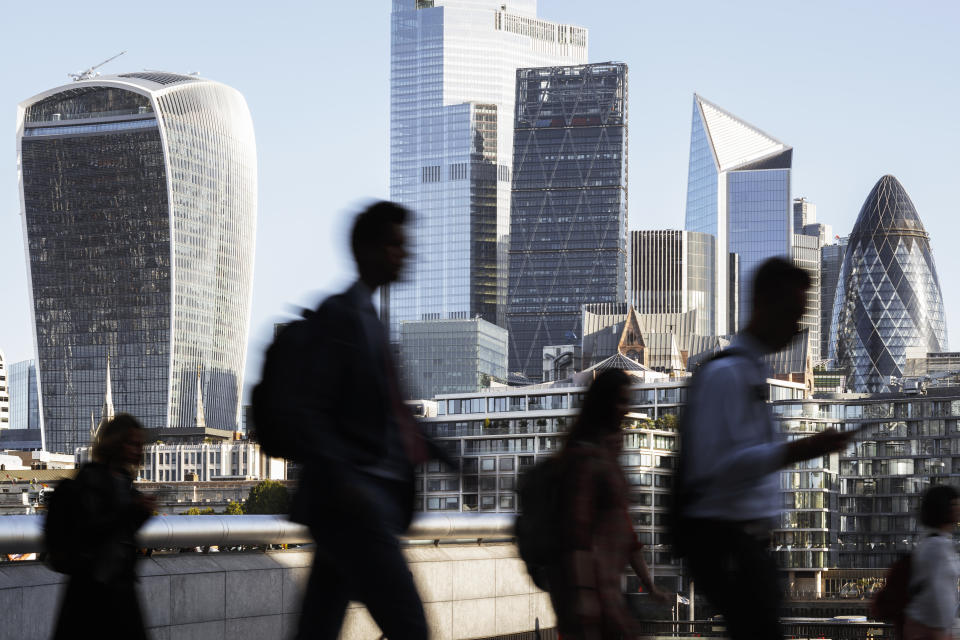 FTSE UK, London, blurred motion of incidental business people walking to work with view of the financial district behind