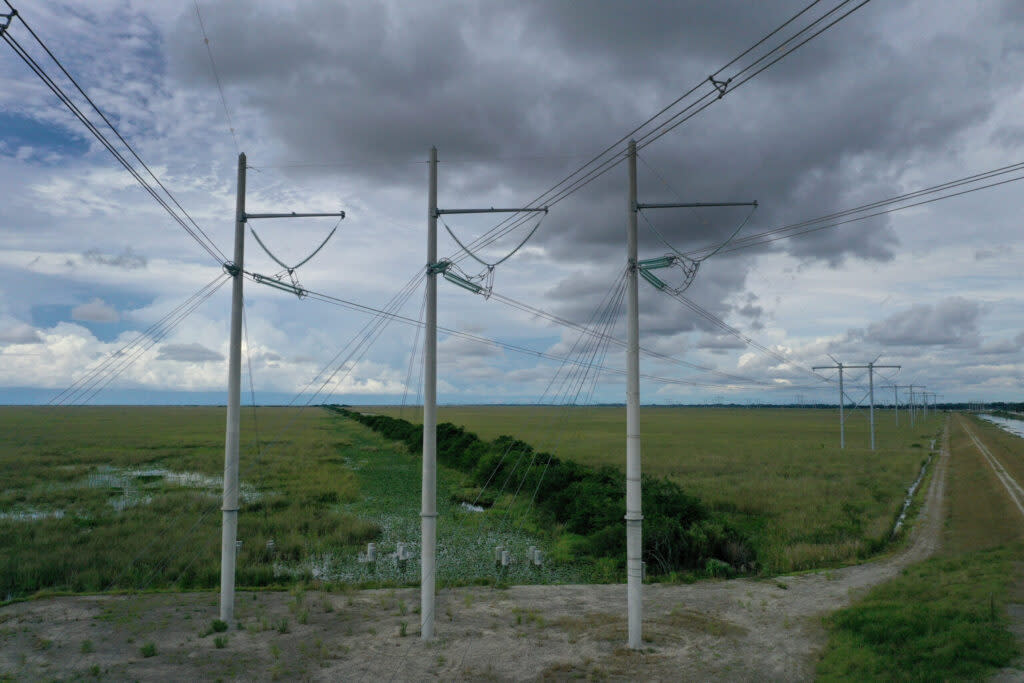 Electric power lines extend into the foreground and background against a cloudy sky.