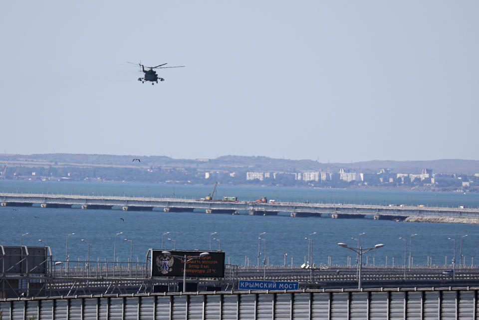 A Russian military helicopter flies over damaged parts of an automobile link of the Crimean Bridge connecting Russian mainland and Crimean peninsula over the Kerch Strait not far from Kerch, Crimea, on Monday, July 17, 2023. An attack before dawn damaged a part of a bridge linking Russia to Moscow-annexed Crimea that is a key supply route for Kremlin forces in the war with Ukraine. The strike Monday has forced the span's temporary closure for a second time in less than a year. (AP Photo)