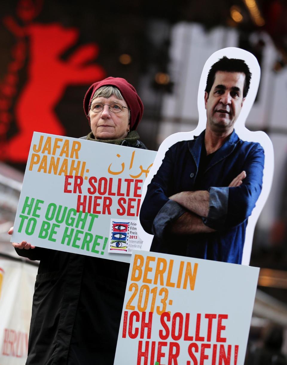 A protester shows a banner next to a portrait of Iranian director Jafar Panahi prior to the screening of the movie 'Closed Curtain' during the 63rd annual Berlin International Film Festival in Berlin, Germany, Tuesday Feb.12. 2013. The movie from the dissident Iranian director that defies a ban on filmmaking and reflects his frustration at being unable to work officially is making its debut at the Berlin film festival. "Closed Curtain" is co-directed by Jafar Panahi and fellow Iranian filmmaker and his longtime friend Kamboziya Partovi. Panahi, who has won awards at several major film festivals in the past, was sentenced to house arrest and a 20-year ban on filmmaking in 2011 after being convicted of "making propaganda" against Iran's ruling system. Partovi presented the movie Tuesday at the Berlin festival, where it's one of 19 films competing for the top Golden Bear award. It's filmed entirely inside a seaside villa, much of the time with curtains drawn, and the two directors are the lead actors. (AP Photo/dpa, Kay Nietfeld)