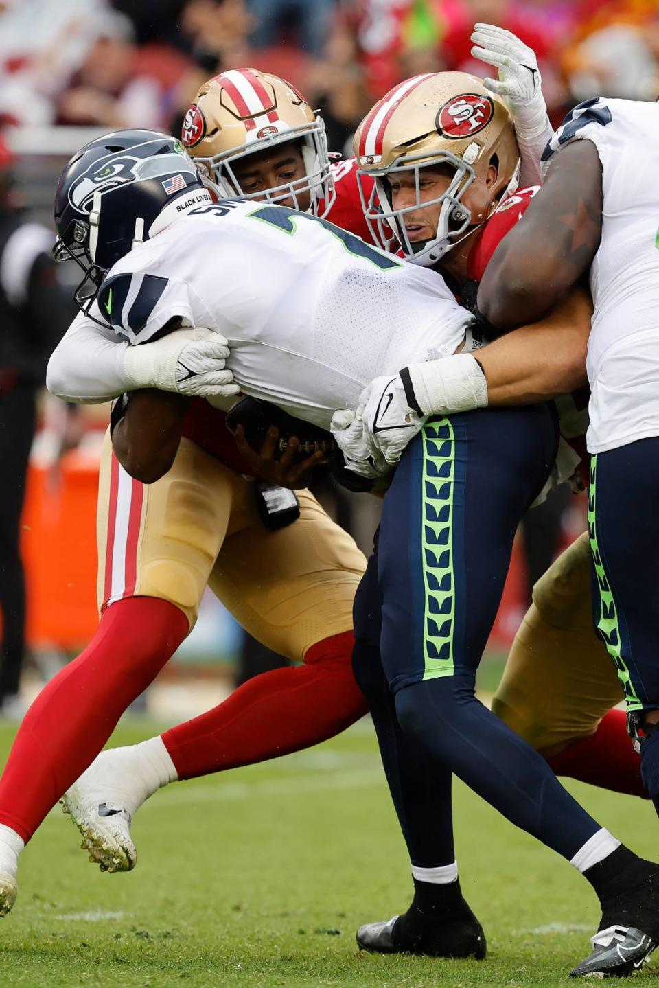 Seattle Seahawks quarterback Geno Smith, foreground, is sacked by San Francisco 49ers defensive end Drake Jackson, middle left, and defensive end Nick Bosa during the second half of an NFL football game in Santa Clara, Calif., Sunday, Sept. 18, 2022. (AP Photo/Josie Lepe)