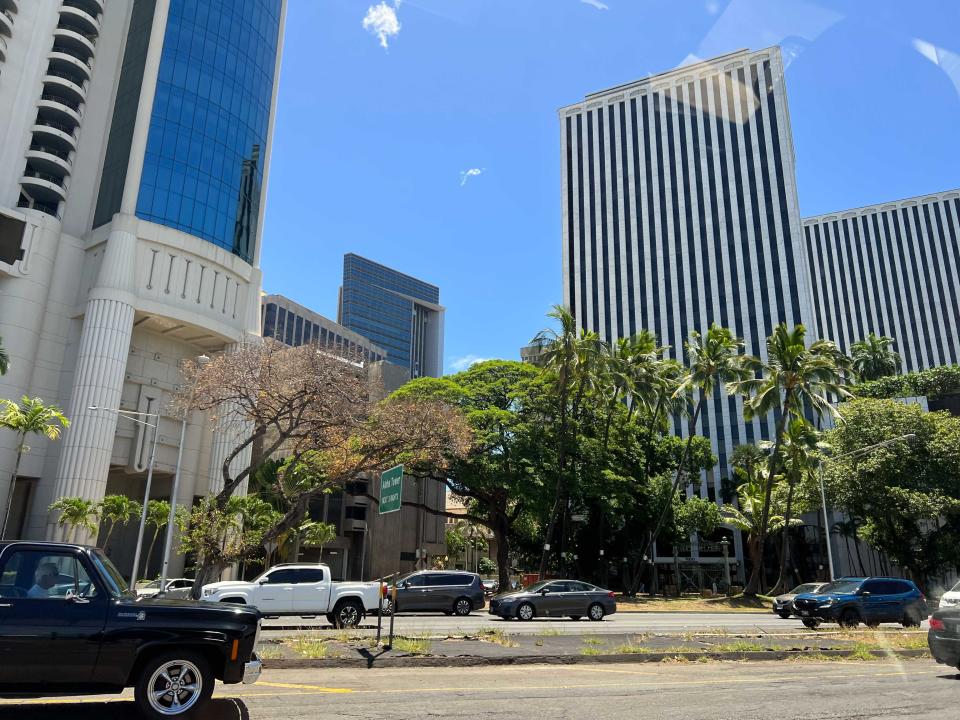 A street with cars and tall commercial buildings.