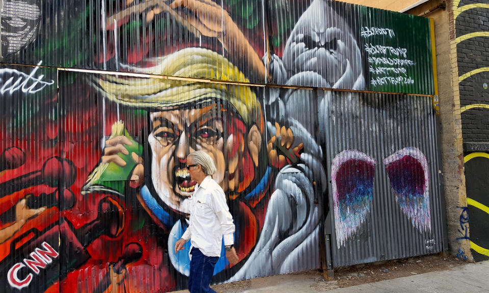 <p>A pedestrian walks past a street mural of Donald Trump in downtown Los Angeles, May 4, 2016. (Nick Ut/AP) </p>