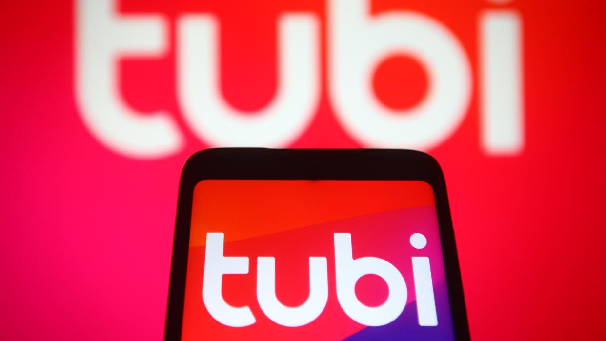  The Tubi logo on a phone in front of the Tubo logo on a bigger screen 