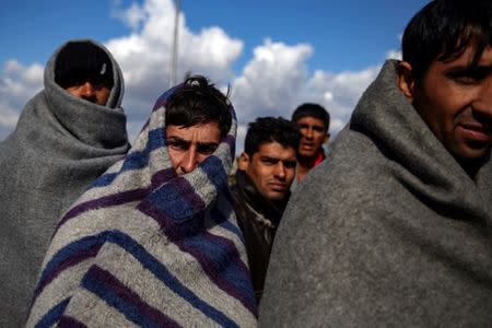 Refugees and migrants try to warm themselves as they take a break at a petrol station before abandoning their trek to the Hungarian border, in the town of Indjija, Serbia October 5, 2016. REUTERS/Marko Djurica