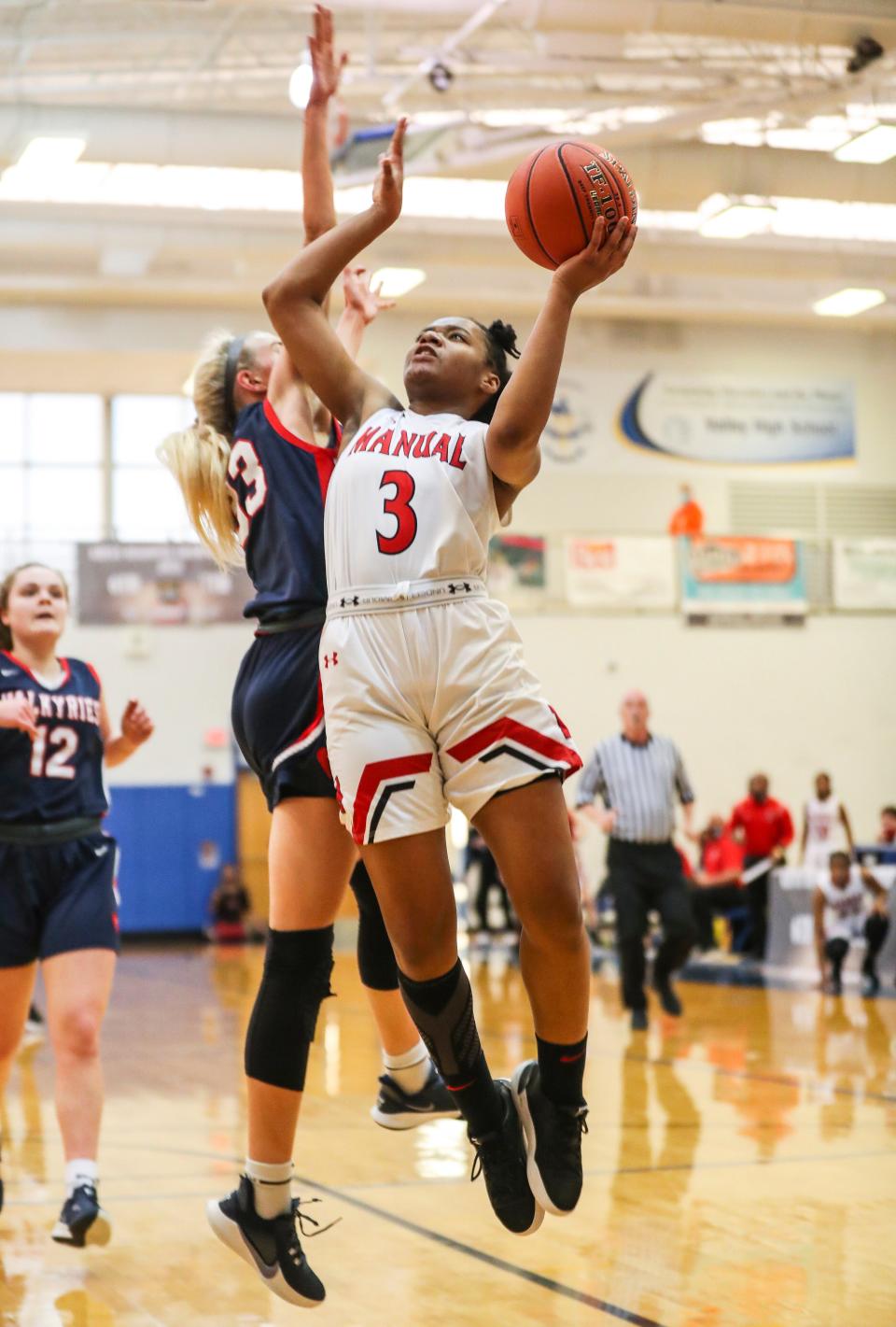 Manual's Jakayla Thompson scores against Sacred Heart's Josie Gilvin at the Girls Seventh Regional semifinal at Valley High School. March 26, 2021
