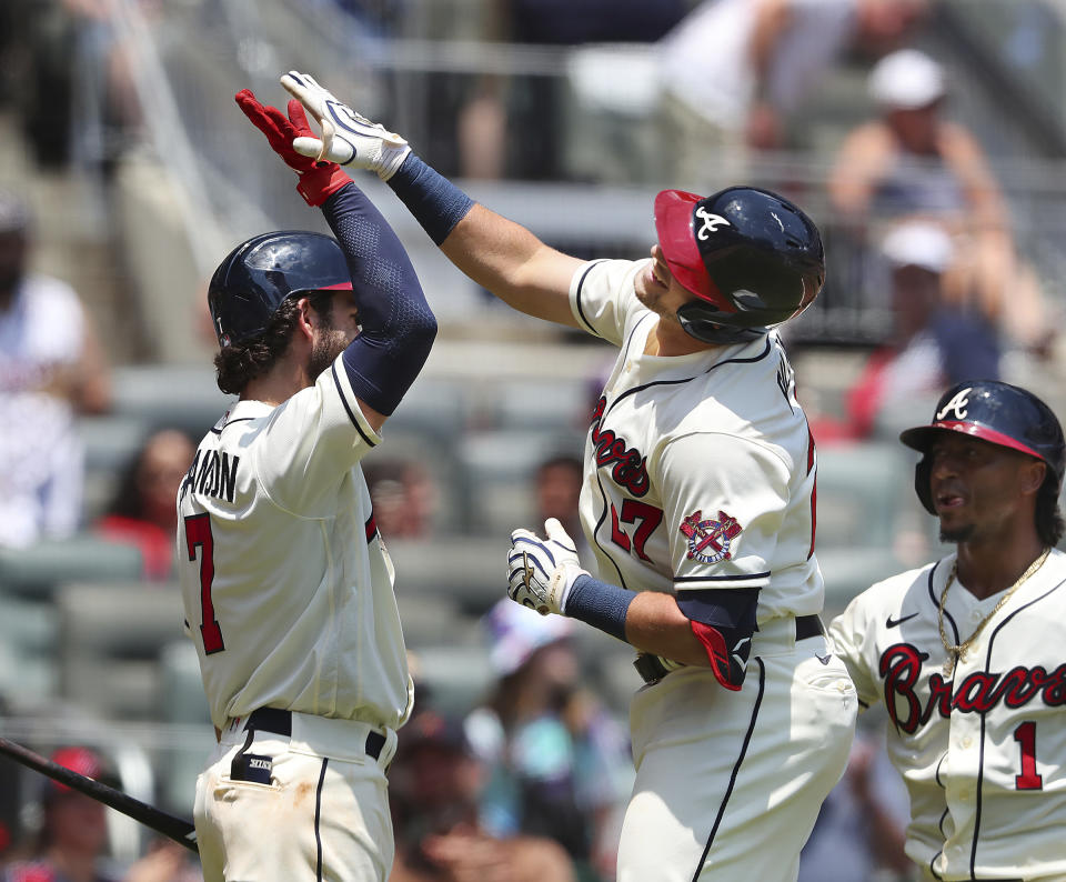 Atlanta Braves' Austin Riley, center, gets some air to high-five teammate Dansby Swanson, left, while celebrating his second home run with Ozzie Albies, right, looking on during the third inning of a baseball game against the Pittsburgh Pirates, Sunday, May 23, 2021, in Atlanta. (Curtis Compton/Atlanta Journal-Constitution via AP)