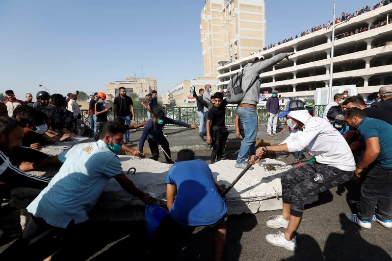 Iraqi demonstrators pull concrete walls at Sinak Bridge during the ongoing anti-government protests, in Baghdad