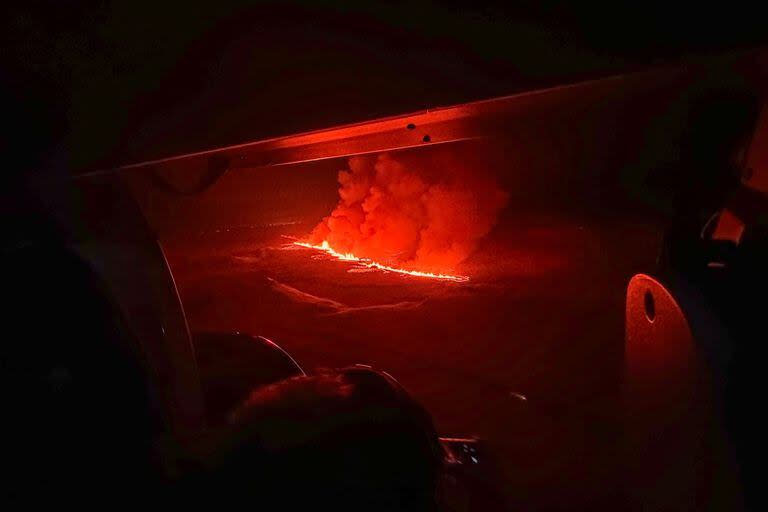 Personal de emergencias y científicos observan el humo y la lava que tiñen el cielo de naranja en esta imagen de la Guardia Costera islandesa sobrevolando una erupción volcánica en la península de Reykjanes, a 3 km al norte de Grindavik, en el oeste de Islandia, el 18 de diciembre de 2023. 