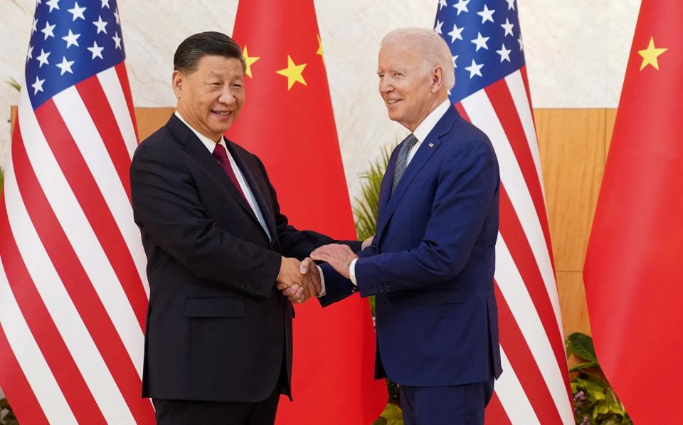 President Biden shakes hands with President Xi Jinping, with their respective flags in the background.