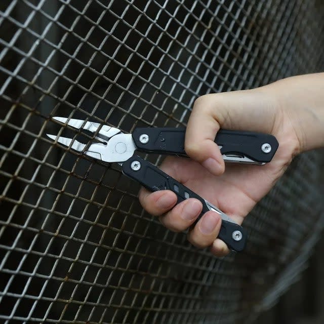Hand holding a multi-tool with pliers extended