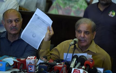 Shahbaz Sharif shows a document as he speaks during a press conference at his political office in Lahore - Credit: AFP
