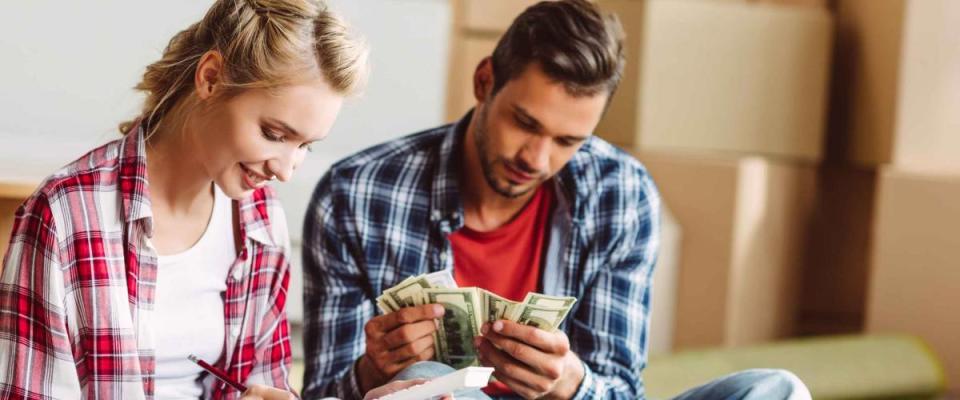 young couple counting money while sitting on floor in new apartment