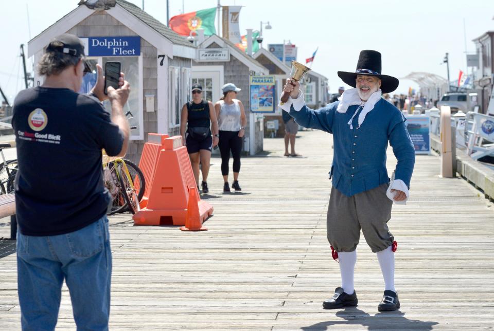 In June 2021, Town Crier Daniel Gómez Llata poses for photos as he walks along MacMillan Pier in Provincetown after greeting ferry passengers.