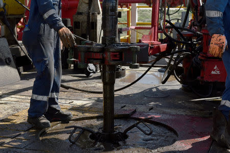 FILE PHOTO: A drilling crew uses a mechanical roughneck machine to thread drill pipe together on an oil rig in the Permian Basin near Wink, Texas U.S. August 22, 2018. REUTERS/Nick Oxford/File Photo