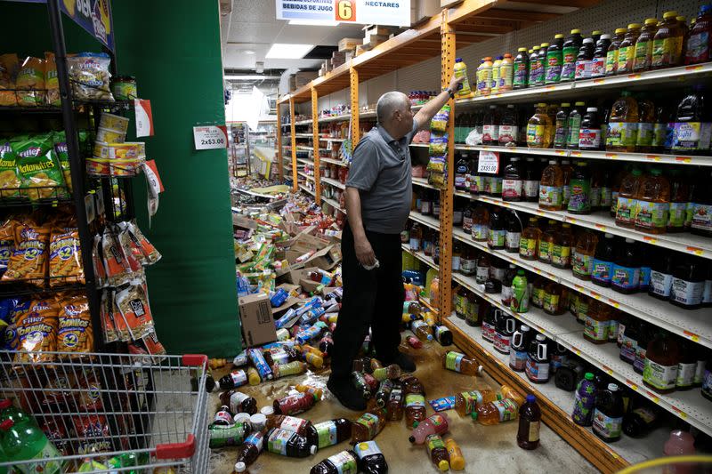 A worker cleans up a shop after an earthquake in Guanica