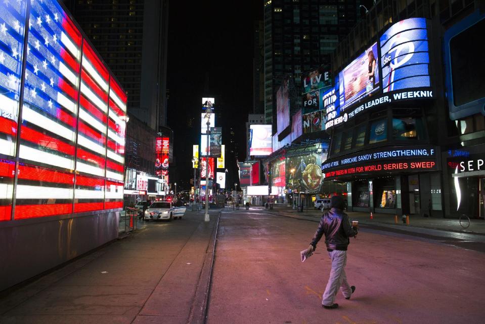 A lone pedestrian walks through an empty Times Square early, Monday, Oct. 29, 2012, in New York. Hurricane Sandy continued on its path Monday, forcing the shutdown of mass transit, schools and financial markets, sending coastal residents fleeing, and threatening a dangerous mix of high winds and soaking rain. (AP Photo/ John Minchillo)