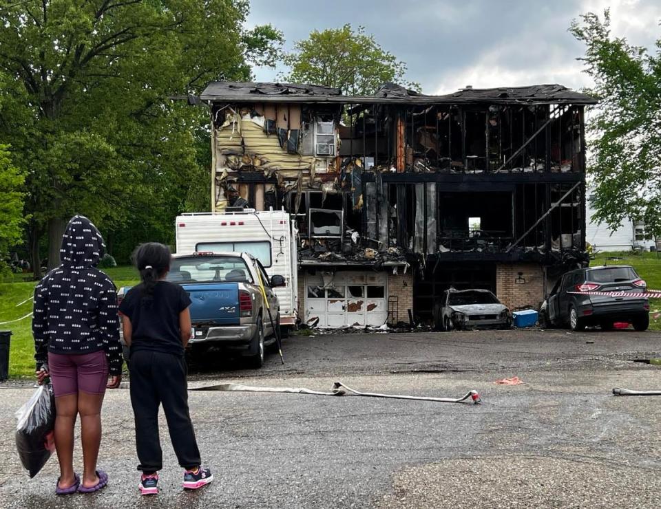 Two children look at the extensive fire damage to a duplex on Saturday afternoon at 3693 Millvale Ave. NE in Plain Township. Nobody was injured in the blaze, which was started by a vehicle that caught fire outside the home.