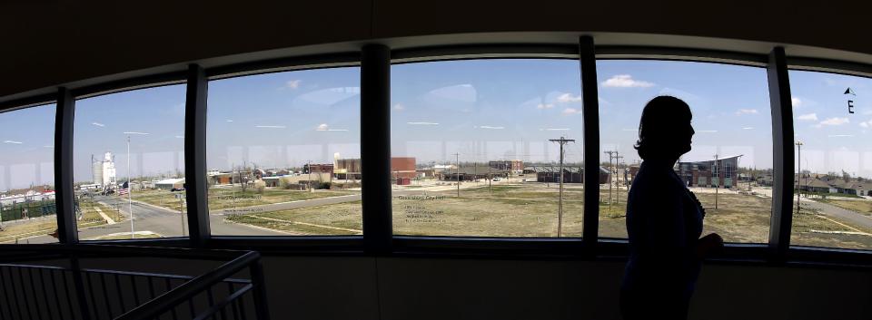 In this photo taken April, 18, 2014, museum director Stacy Barnes looks out over scattered rebuilt homes and business from a viewing deck at the rebuilt Big Well Museum in Greensburg, Kan. Seven years after an EF-5 tornado destroyed most of the community of 1,500, many of the town's destroyed civic buildings have been rebuilt but a rebound in population is slow in coming. (AP Photo/Charlie Riedel)