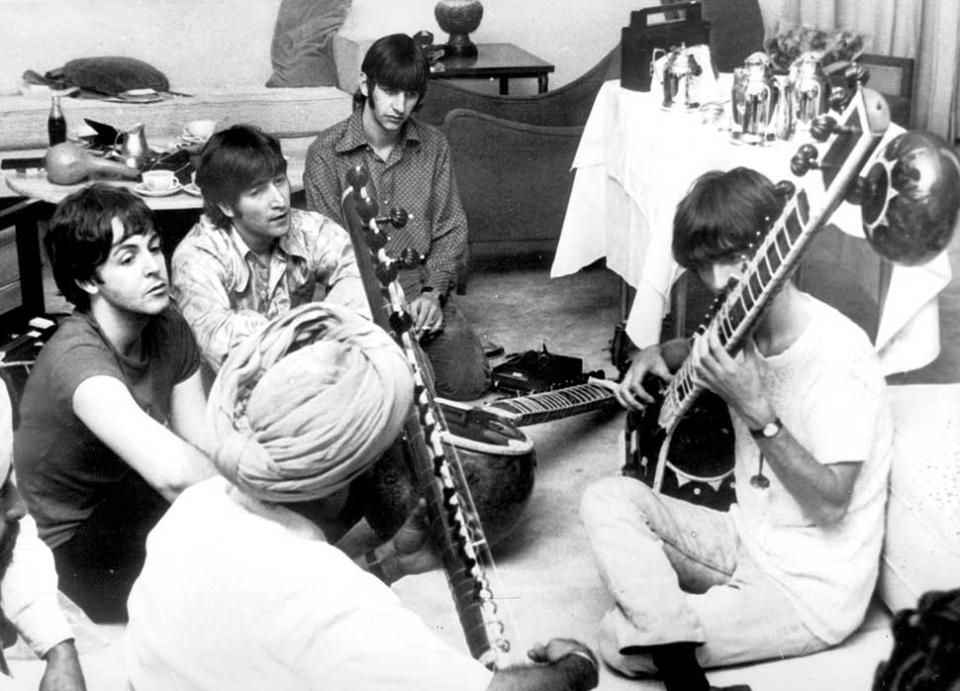 eatle George Harrison receiving instruction in playing the sitar from a Sikh teacher as the other members of the Beatles look on in quiet fascination.