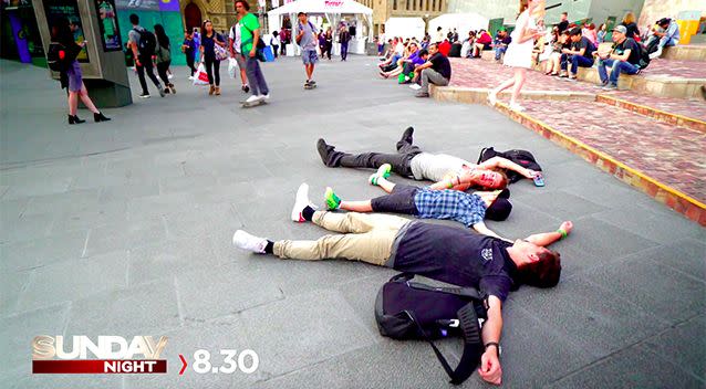 Cameron's friends Adam and James lie next to him in the middle of Federation Square.