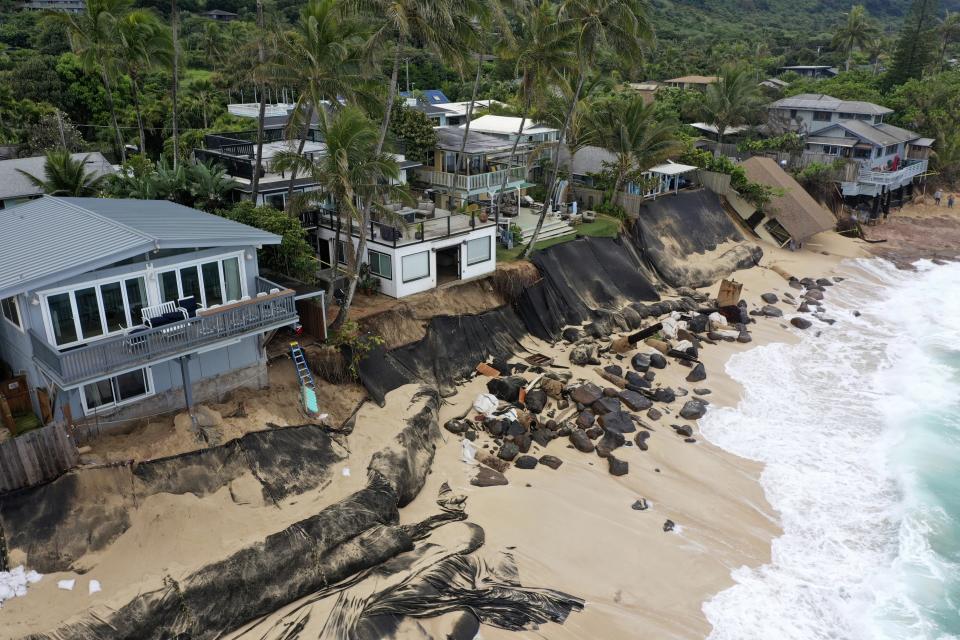 This photo provided by the Hawaii Department of Land and Natural Resources, shows a home, right, after it collapsed onto a beach on Feb. 28, 2022, in Haleiwa, Hawaii. Rising seas and more intense storms are encroaching on coastal properties. Some coastal erosion removes sand surrounding cesspools and pulls sewage out to sea. (Dan Dennison/Hawaii Department of Land and Natural Resources via AP)