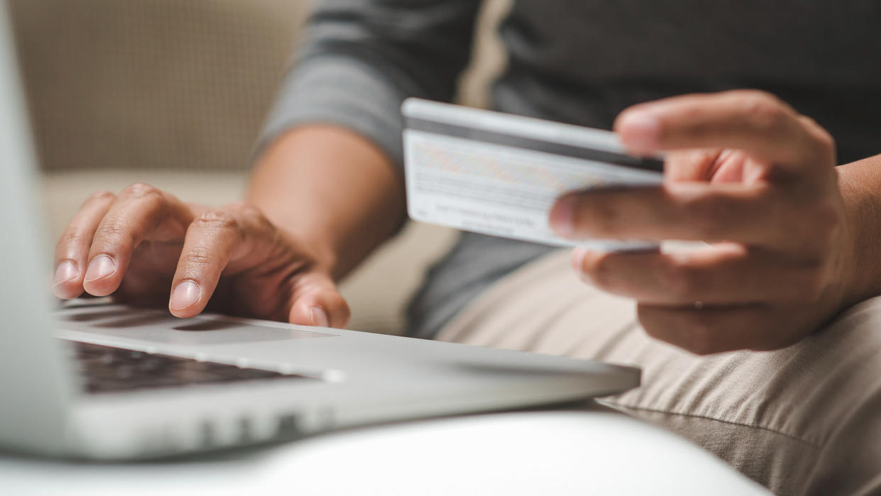 Internet shopper entering credit card information using laptop keyboard.