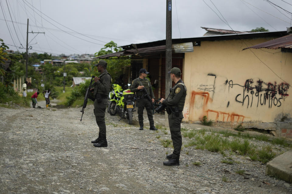 Police stand guard by a building covered in gang-related graffiti in Buenaventura, Colombia, Thursday, Aug. 17, 2023. Two gangs, Los Shottas and Los Espartanos, are the latest to lay siege to Buenaventura, Colombia’s busiest port from which drugs pour out to the rest of the world. (AP Photo/Fernando Vergara)