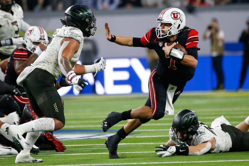 Utah quarterback Cameron Rising, right, eludes Oregon linebacker Noah Sewell during the second quarter of the Pac-12 championship game.