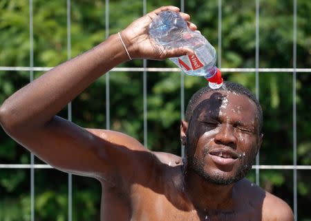 An asylum seeker sprays water on his face while taking part in the soccer tournament "All on the pitch" organised by NGO's and Belgian Football Association at the occasion of the World Refugee Day, in Deurne, Belgium June 20, 2018. REUTERS/Yves Herman