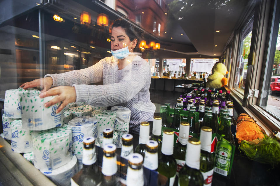 Sarah Rivas an employee at Annie's Paramount Steakhouse in Dupont Circle district of Washington, arranges display of toilet paper and liquor for carry out orders Monday, April 13, 2020. The steakhouse closed due to the coronavirus pandemic but is opened for carry out orders offering the steakhouse's menu, liquor and groceries. (AP Photo/Manuel Balce Ceneta)