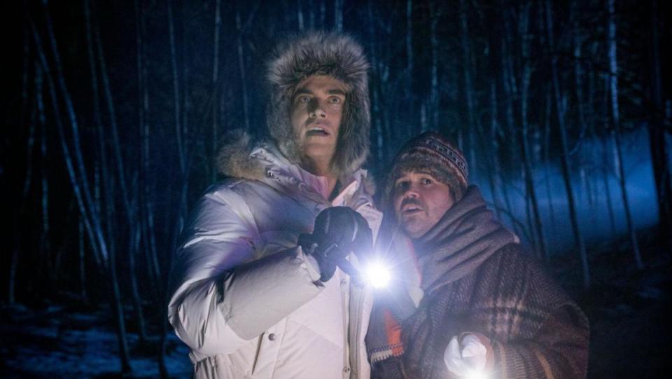 A still from Werewolves Within shows Cheyenne Jackson and Harvey Guillén hugging in a snowy forest 